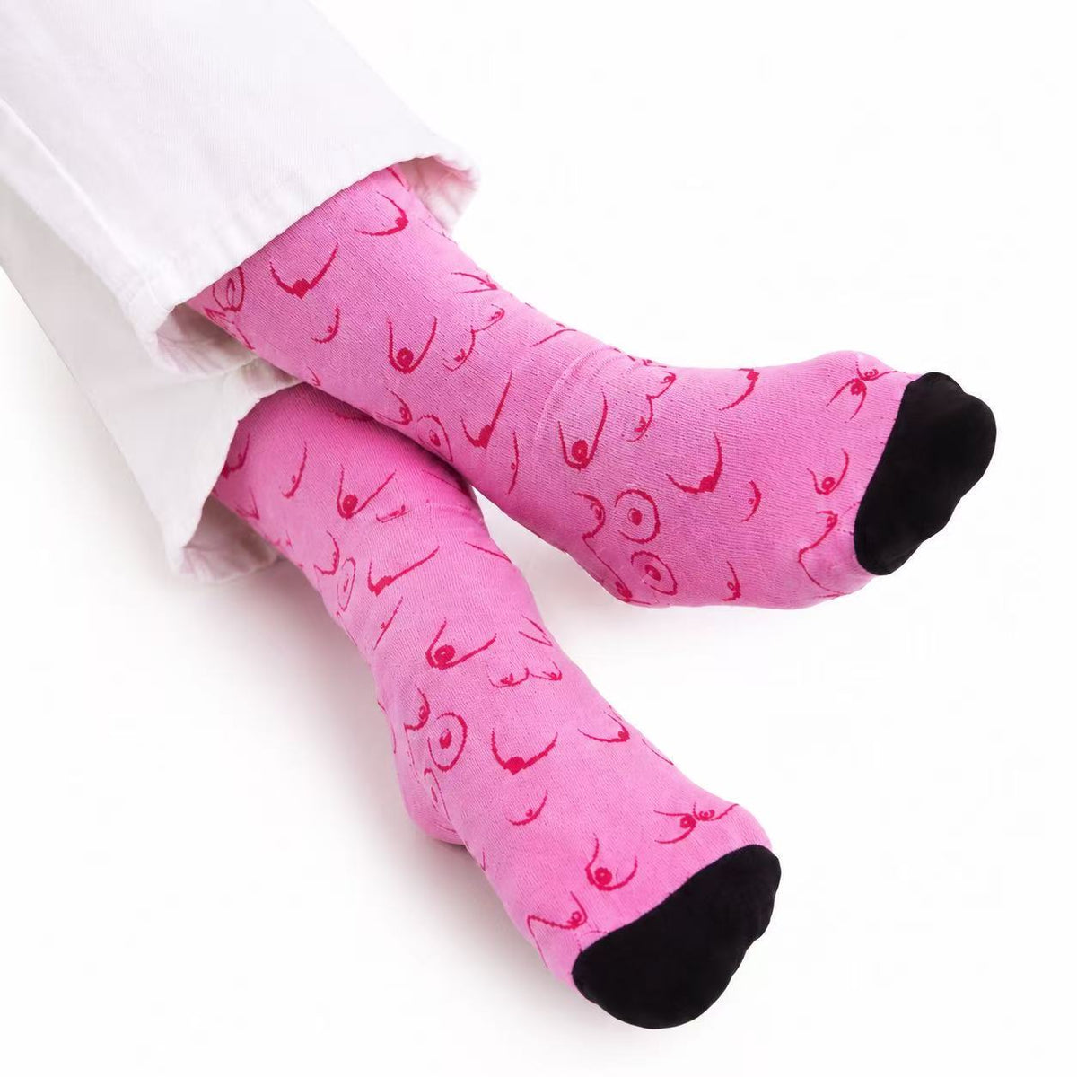 Pink novelty socks with a red graphic print of stylized female breast, worn with white pants on a white background.