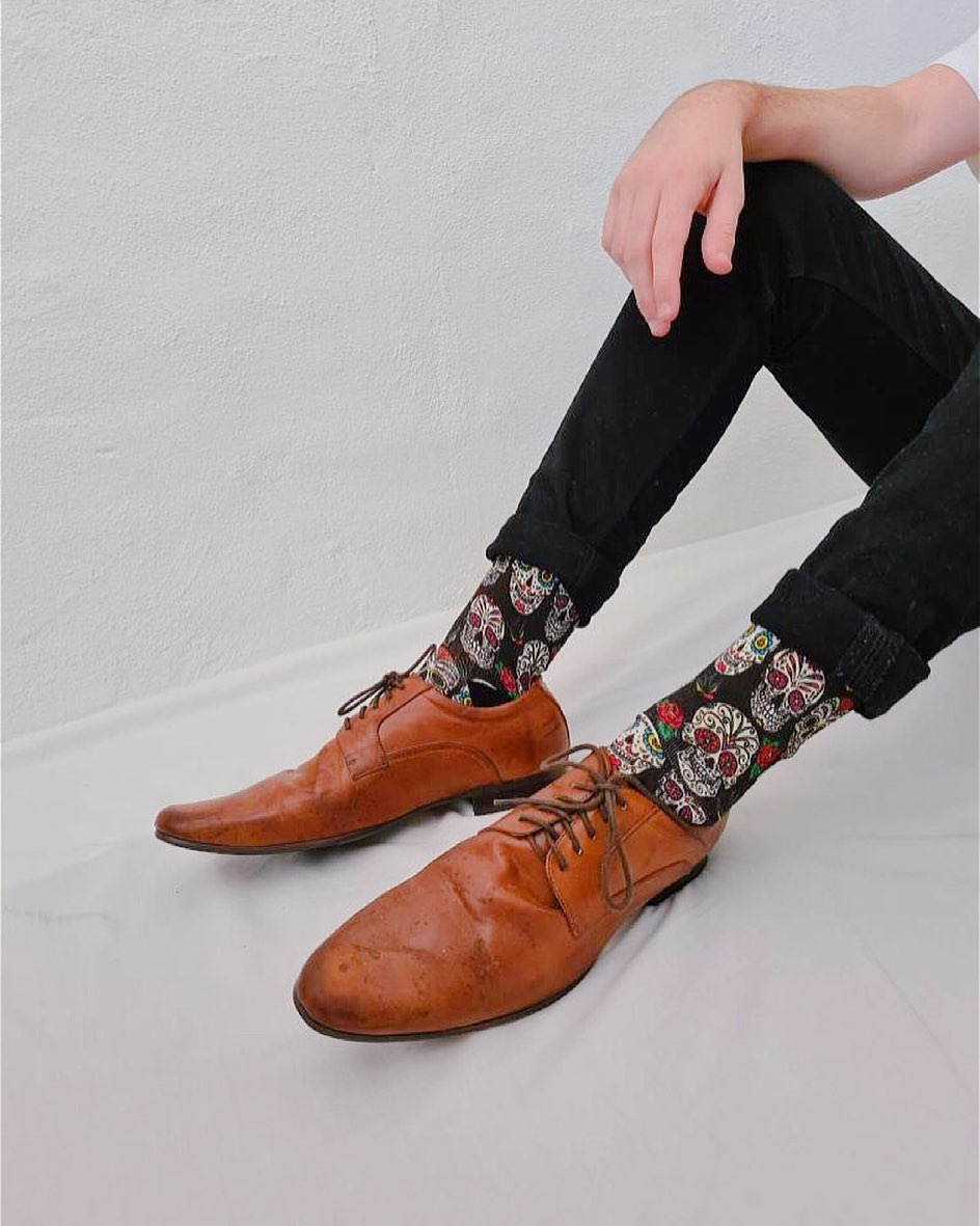 Men wearing black Sugar Skull bamboo socks with colourful Day of the Dead skull pattern and brown leather shoes. Soft bamboo blend novelty socks designed in Australia by RedFoxSox.